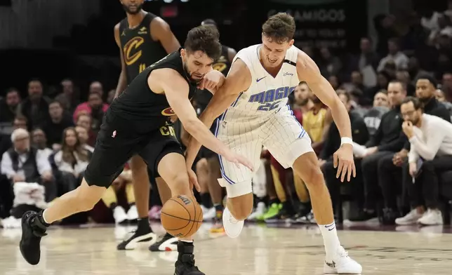 Cleveland Cavaliers guard Ty Jerome, left, and Orlando Magic forward Franz Wagner, right, reach for a loose ball in the first half of an NBA basketball game, Friday, Nov. 1, 2024, in Cleveland. (AP PhotoSue Ogrocki)