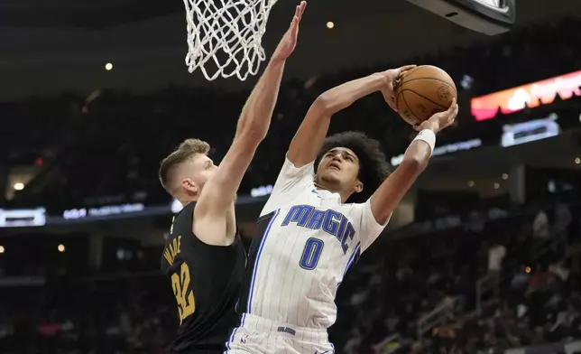 Orlando Magic guard Anthony Black (0) shoots as Cleveland Cavaliers forward Dean Wade (32) defends in the first half of an NBA basketball game, Friday, Nov. 1, 2024, in Cleveland. (AP PhotoSue Ogrocki)