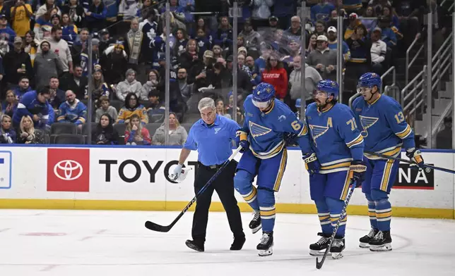 St. Louis Blues' Philip Broberg (6) is assisted off the ice by teammates during the second period of an NHL hockey game against the Toronto Maple Leafs, Saturday, Nov. 2, 2024, in St. Louis. (AP Photo/Connor Hamilton)