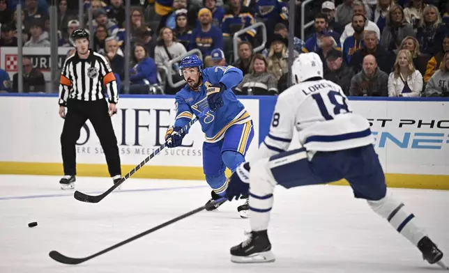 St. Louis Blues' Justin Faulk, center, passes the puck as Toronto Maple Leafs' Steven Lorentz (18) defends during the second period of an NHL hockey game Saturday, Nov. 2, 2024, in St. Louis. (AP Photo/Connor Hamilton)