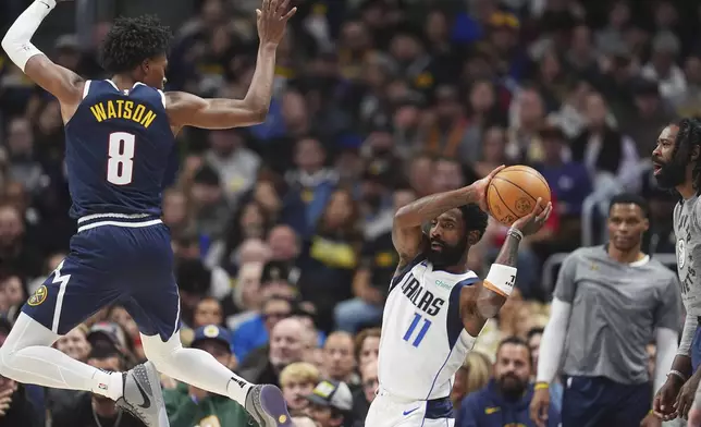 Dallas Mavericks guard Kyrie Irving, right, looks to pass the ball as Denver Nuggets forward Peyton Watson defends in the second half of an NBA basketball game, Sunday, Nov. 10, 2024, in Denver. (AP Photo/David Zalubowski)