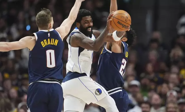 Dallas Mavericks guard Kyrie Irving, center, passes the ball as he drives between Denver Nuggets guards Christian Braun, left, and Jamal Murray in the second half of an NBA basketball game, Sunday, Nov. 10, 2024, in Denver. (AP Photo/David Zalubowski)