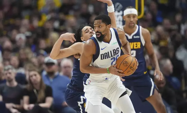 Dallas Mavericks guard Spencer Dinwiddie, front, looks to pass the ball as Denver Nuggets guard Julian Strawther, center, and forward Zeke Nnaji defend in the second half of an NBA basketball game, Sunday, Nov. 10, 2024, in Denver. (AP Photo/David Zalubowski)