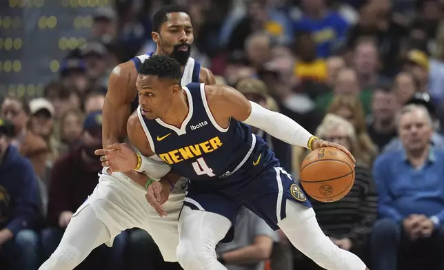 Denver Nuggets guard Russell Westbrook (4) drives past Dallas Mavericks guard Spencer Dinwiddie, top, in the first half of an NBA basketball game Sunday, Nov. 10, 2024, in Denver. (AP Photo/David Zalubowski)