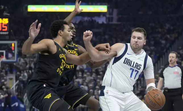 Dallas Mavericks guard Luka Doncic (77) drives to the basket against Golden State Warriors forward Trayce Jackson-Davis, left, and forward Andrew Wiggins during the first half of an Emirates NBA Cup basketball game in San Francisco, Tuesday, Nov. 12, 2024. (AP Photo/Jeff Chiu)