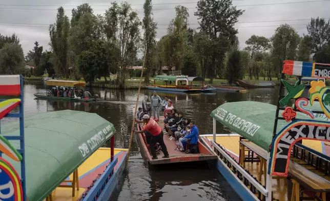 Amateur soccer players and families travel in a traditional canoe in the Xochimilco borough of Mexico City, on Sunday, October 20, 2024. (AP Photo/Felix Marquez)