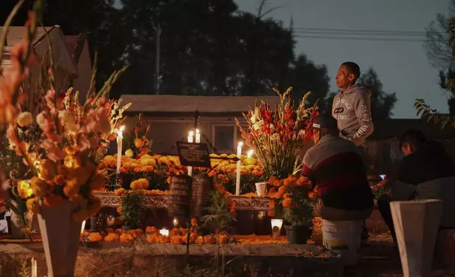 Families gather by the tomb of their dearly departed, as they celebrate the Day of the Dead, at the San Gregorio Atlapulco cemetery on the outskirts of Mexico City, Friday, Nov. 1, 2024. (AP Photo/Moises Castillo)