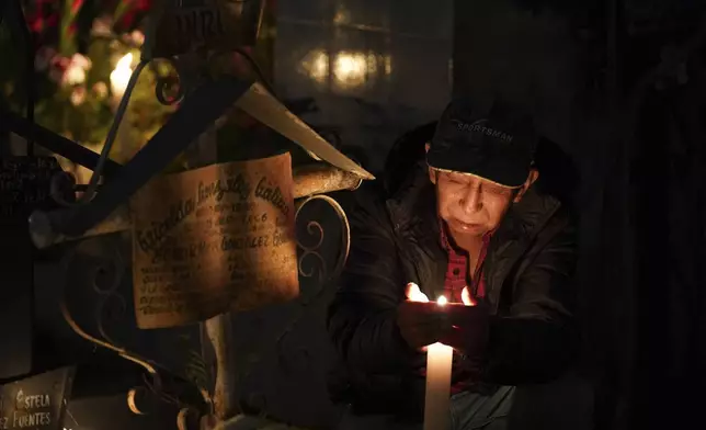 A man sits at the tomb of a dearly departed celebrating the Day of the Dead, at the San Gregorio Atlapulco cemetery on the outskirts of Mexico City, Friday, Nov. 1, 2024. (AP Photo/Moises Castillo)