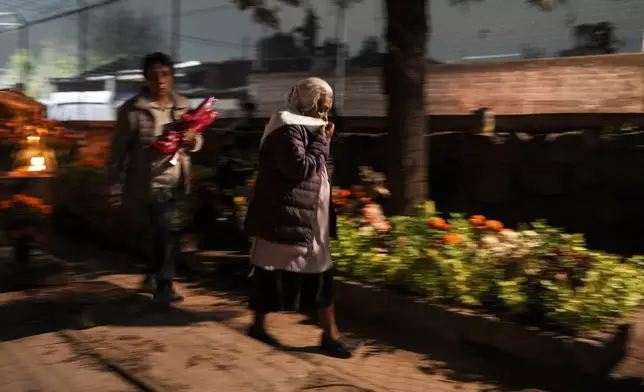 Women arrive at the cemetery to keep company with their dearly departed, as they celebrate Day of the Dead, at the San Gregorio Atlapulco on the outskirts of Mexico City, Friday, Nov. 1, 2024. (AP Photo/Moises Castillo)