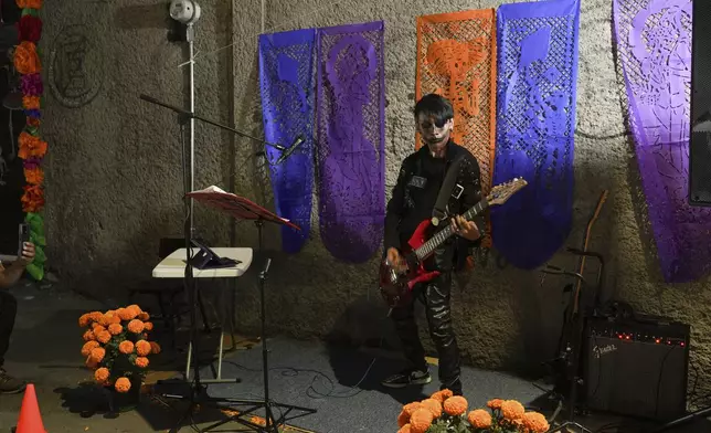 A musician performs people celebrate the Day of the Dead, near the San Gregorio Atlapulco cemetery on the outskirts of Mexico City, Friday, Nov. 1, 2024. (AP Photo/Moises Castillo)