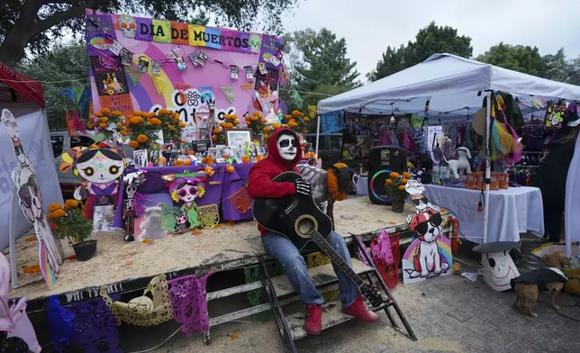 A pet owner poses with his dog in front of a Day of the Dead altar honoring the memory of pets that have passed on, in Mexico City, Sunday, Oct. 27, 2024. (AP Photo/Fabiola Sanchez)