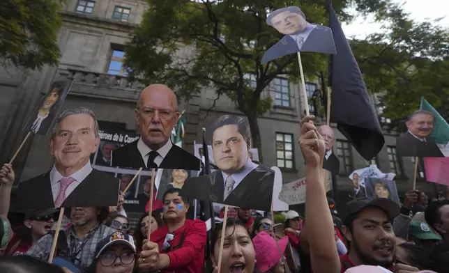 Justice employees hold up cutouts of Supreme Court Justices in a show of support as they discuss a draft ruling that proposes the partial invalidation of the judicial reform approved by Congress, in Mexico City, Tuesday, Nov. 5, 2024. (AP Photo/Fernando Llano)