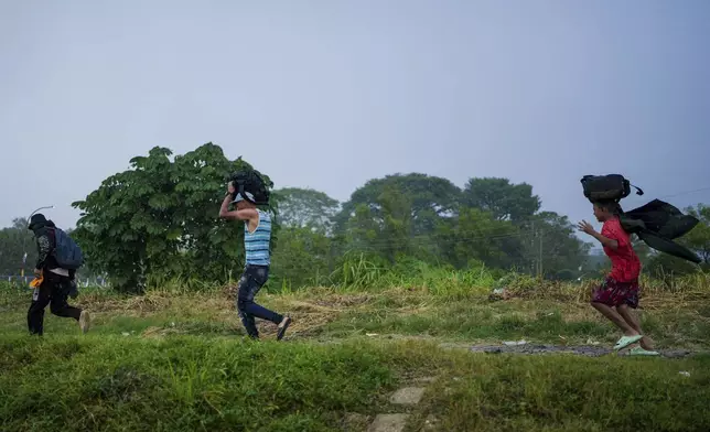 Migrants run in the rain after arriving at a makeshift shelter in Huixtla, Chiapas state, Mexico, Wednesday, Nov. 6, 2024, hoping to reach the country's northern border and ultimately the United States. (AP Photo/Moises Castillo)