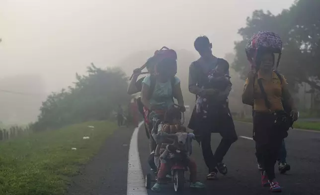 Migrants walk through the morning fog on the highway in Huixtla, southern Mexico, heading toward the country's northern border and ultimately the United States, Thursday, Nov. 7, 2024. (AP Photo/Moises Castillo)