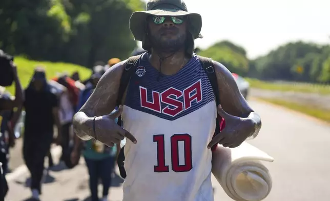 A migrant strikes a pose as he walks alongside the highway in Escuintla, southern Mexico, heading toward the country's northern border and ultimately the United States, Thursday, Nov. 7, 2024. (AP Photo/Moises Castillo)