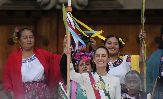 Newly inaugurated Mexican President Claudia Sheinbaum smiles as she holds the staff of office during a rally in the Zócalo, Mexico City's main square, Oct. 1, 2024. (AP Photo/Eduardo Verdugo, File)