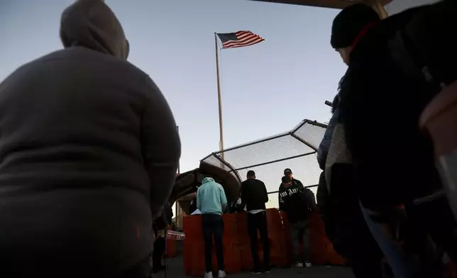 FILE - Migrants line up at the Paso del Norte international bridge to present to U.S. agents documents requesting an appointment to apply for asylum, in Ciudad Juarez, Mexico, Nov. 5, 2024. (AP Photo/Christian Chavez, File)