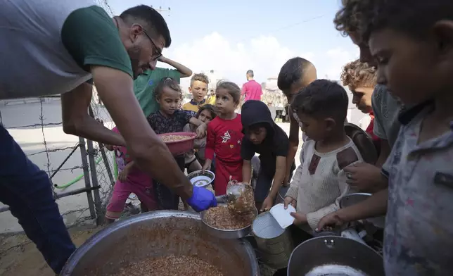 FILE - Displaced Palestinian children queue for food in a camp in Deir al-Balah, Gaza Strip, Friday, Oct. 18, 2024. (AP Photo/Abdel Kareem Hana, File)