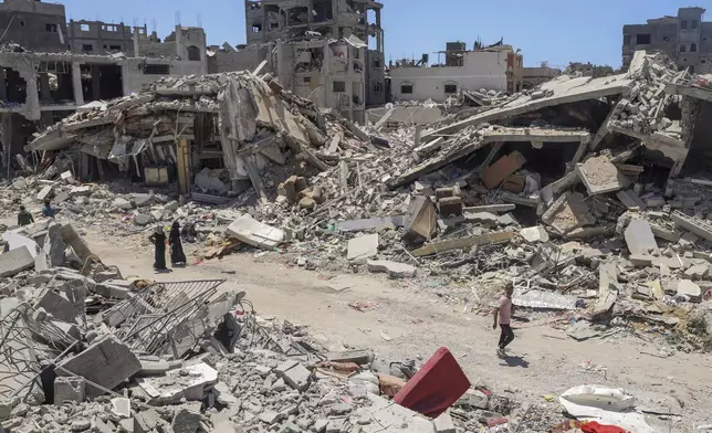 FILE - Palestinians walk through the destruction in the wake of an Israeli air and ground offensive in Jebaliya, northern Gaza Strip, on May 30, 2024. (AP Photo/Enas Rami, File)