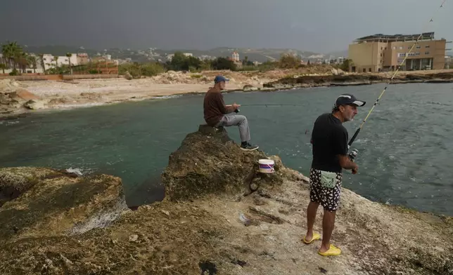 Lebanese fishermen cast their fishing rods at a beach in Batroun, northern Lebanon, Saturday, Nov. 2, 2024, where Lebanese officials say a ship captain was taken away by a group of armed men who landed on a coast north of Beirut and they're investigating whether Israel was involved. (AP Photo/Hussein Malla)