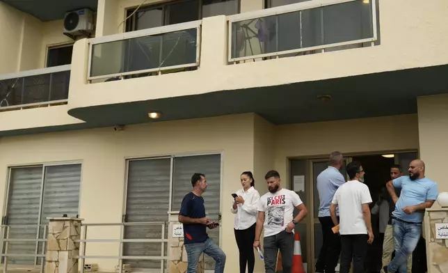 Residents stand at the entrance of a building in Batroun, northern Lebanon, Saturday, Nov. 2, 2024, where Lebanese officials say a ship captain was taken away by a group of armed men who landed on a coast north of Beirut and they're investigating whether Israel was involved. (AP Photo/Hussein Malla)