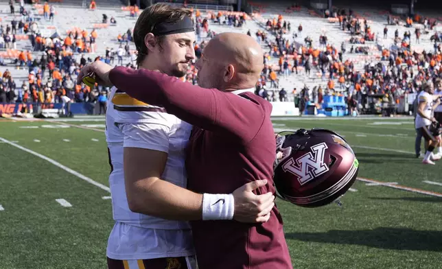 Minnesota head coach P.J. Fleck hugs quarterback Max Brosmer after the teams 25-17 win over Illinois in an NCAA college football game Saturday, Nov. 2, 2024, in Champaign, Ill. (AP Photo/Charles Rex Arbogast)