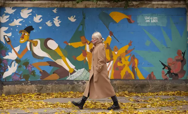 A woman walks by graffiti done in 2016 by Moldovan artists celebrating 25 years since the country declared its independence from the Soviet Union, in Chisinau, Moldova, Monday, Nov. 4, 2024. (AP Photo/Vadim Ghirda)