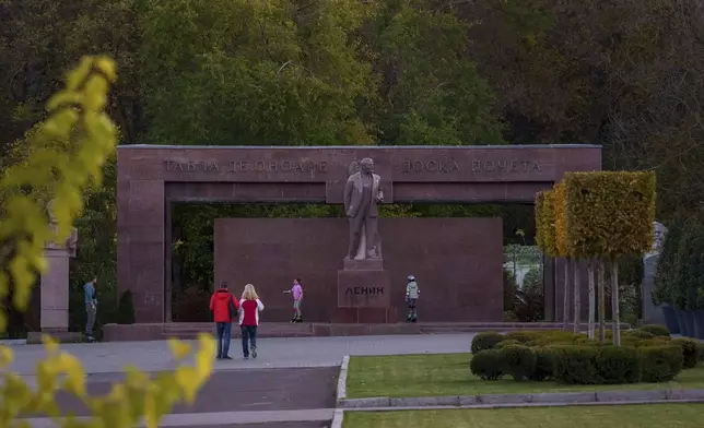 Children skate next to a statue of Lenin, with the words "Board of Honor" written in Cyrillic in Romanian and Russian in Chisinau, Moldova, Friday, Nov. 1, 2024. (AP Photo/Vadim Ghirda)