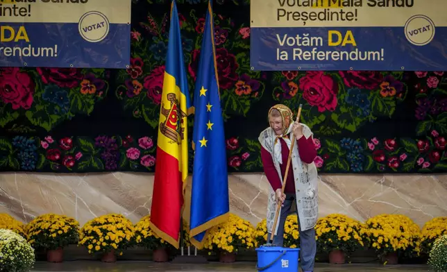 FILE - A woman mops a stage before an electoral rally of Moldova's President Maia Sandu in Magdacesti, Moldova, Oct. 17, 2024. (AP Photo/Vadim Ghirda, File)