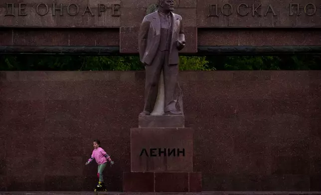 A girl skates next to a statue of Lenin, with the words "Board of Honor" written in Cyrillic in Romanian and Russian in Chisinau, Moldova, Friday, Nov. 1, 2024. (AP Photo/Vadim Ghirda)