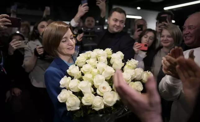 Moldova's President Maia Sandu smiles while holding a bouquet of flowers as she celebrates with supporters the preliminary results of the presidential election runoff, in Chisinau, Moldova, Sunday, Nov. 3, 2024. (AP Photo/Vadim Ghirda)