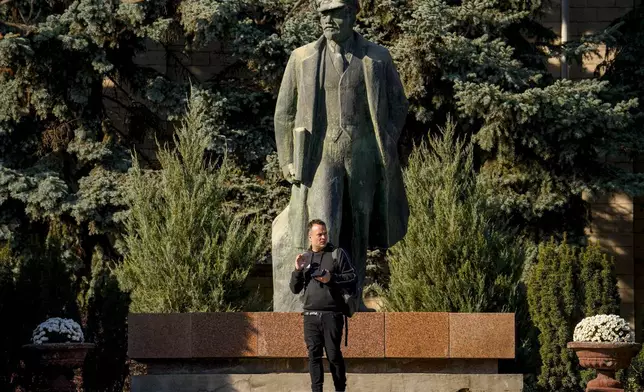 A man backdropped by a statue of Lenin, checks his phone in Comrat, the capital of Gagauzia, an autonomous part of Moldova, Saturday, Nov. 2, 2024, ahead of a presidential election runoff taking place on Nov. 3. (AP Photo/Vadim Ghirda)