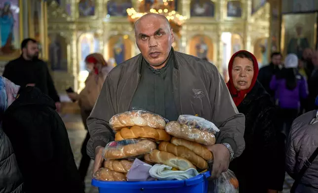 A cleric carries loafs of bread offered in memory of the departed at the end of a religious service inside the Saint John the Baptist cathedral in Comrat, the capital of Gagauzia, an autonomous part of Moldova, Saturday, Nov. 2, 2024, ahead of a presidential election runoff taking place on Nov. 3. (AP Photo/Vadim Ghirda)