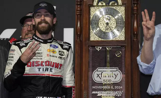 Ryan Blaney, front left, poses with the trophy in Victory Lane after winning a NASCAR Cup Series auto race at Martinsville Speedway in Martinsville, Va., Sunday, Nov. 3, 2024. (AP Photo/Chuck Burton)