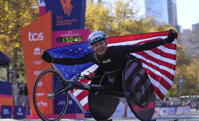 Susannah Scaroni crosses poses for photographs after winning the women's wheelchair division of the New York City Marathon, Sunday, Nov. 3, 2024, in New York. (AP Photo/Frank Franklin II)