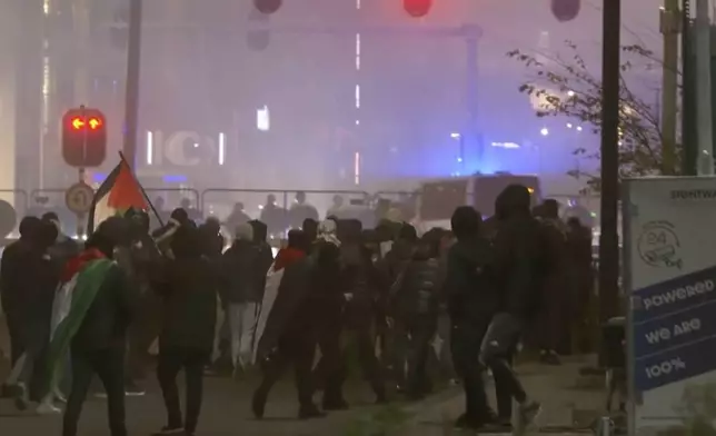 In this image taken from video, a group of pro-Palestinian protesters walk toward police line, with police vans driving in the background, near the soccer stadium in Amsterdam, Netherlands, Thursday, Nov. 7, 2024. (RTL Nieuws via AP)