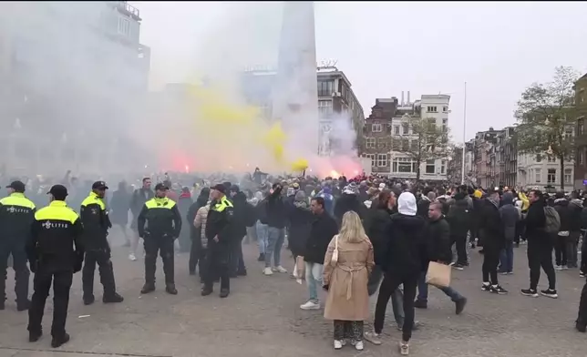 In this image taken from video, police stand guard as Maccabi Tel Aviv supporters light flares at the Dam square, in Amsterdam, the Netherlands, Thursday, Nov. 7, 2024. (AP Photo InterVision)