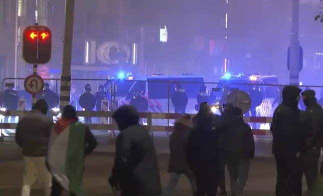 In this image taken from video, a group of pro-Palestinian protesters walk toward police line, with police vans driving in the background, near the soccer stadium in Amsterdam, Netherlands, Thursday, Nov. 7, 2024. (RTL Nieuws via AP)