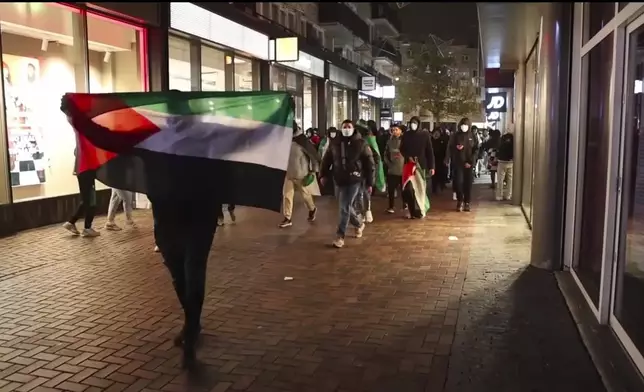 In this image taken from video, pro-Palestinian supporters march with Palestinian flags near the Ajax stadium in Amsterdam, the Netherlands, Thursday, Nov. 7, 2024. (AP Photo InterVision)