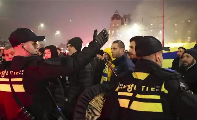 In this image taken from video, police escort Maccabi Tel Aviv supporters to the metro station leading them to the Ajax stadium, after pro-Palestinian supporters marched near the stadium, in Amsterdam, the Netherlands, Thursday, Nov. 7, 2024. (AP Photo InterVision)