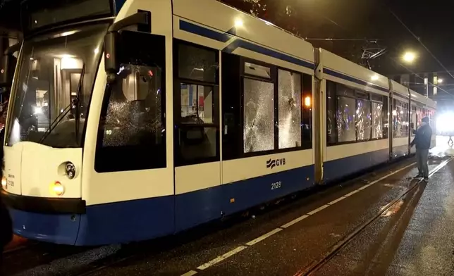 In this image taken from video, a person looks at a damaged tram in Amsterdam, Monday Nov. 11, 2024, as the city is facing tensions following violence last week. (AP Photo)