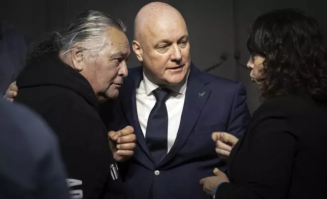 New Zealand's Prime Minister Christopher Luxon, center, talks with survivor Whiti Ronaki, left, and Laura Cherrington following his "formal and unreserved" apology in Parliament for the widespread abuse, torture and neglect of hundreds of thousands of children and vulnerable adults in care, in Wellington, New Zealand Tuesday, Nov. 12, 2024. (Monique Ford/Stuff via AP)