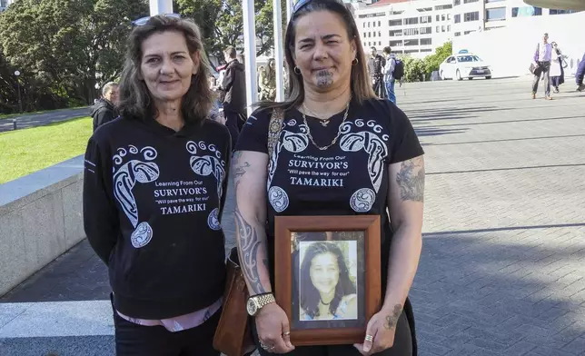 Gina, right, and Tanya Sammons hold a photo of their late sister Alva as they arrive at Parliament House in Wellington, New Zealand, ahead of the apology to the survivors of abuse in state, faith-based and foster care over a period of seven decades, Tuesday, Nov. 12, 2024. (AP Photo/Charlotte Graham-McLay )