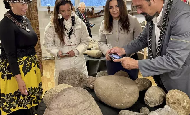 In this photo provided by the Kon-Tiki Museum press service on Wednesday, Nov. 13, 2024, people look at artifacts and human remains taken from Easter Island, also known as Rapa Nui, by a Norwegian explorer in the late 1940s, during the "repatriation" ceremony at the Kon Tiki Museum in Oslo, Norway, Tuesday, Nov. 12, 2024. (Kon-Tiki Museum press service via AP)