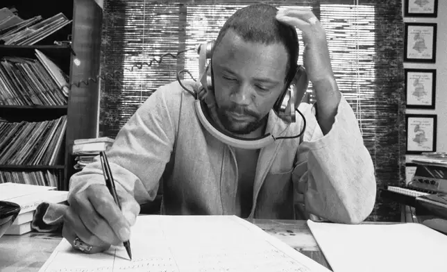 FILE - Composer Quincy Jones at his home studio in October 1974 writing music, listening to a recording on his headphones. (AP Photo/George Brich, File)