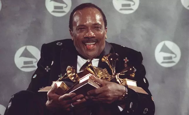 FILE - Quincy Jones cradles his Grammy awards including the album of the year award, for his eclectic album "Back on the Block" during the 33rd annual Grammy Awards, at New York's Radio City Music Hall night of Feb.20,1991. Quincy Jones died at age 91. (AP Photo/Susan Ragan, File)