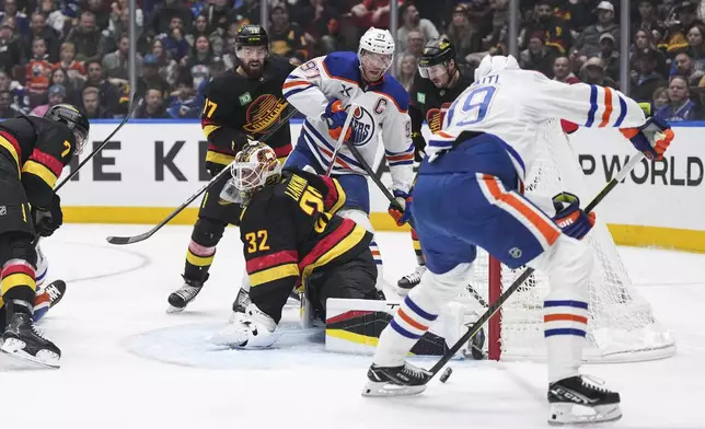 Edmonton Oilers' Leon Draisaitl, front right, scores against Vancouver Canucks goalie Kevin Lankinen (32) as Filip Hronek (17) and Edmonton's Connor McDavid (97) watch during the first period of an NHL hockey game in Vancouver, on Saturday, Nov. 9, 2024. (Darryl Dyck/The Canadian Press via AP)