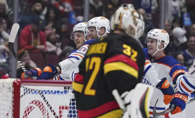 Edmonton Oilers' Mattias Janmark, back from left to right, Corey Perry and Ty Emberson celebrate Perry's goal against Vancouver Canucks goalie Kevin Lankinen during the second of an NHL hockey game in Vancouver, on Saturday, Nov. 9, 2024. (Darryl Dyck/The Canadian Press via AP)