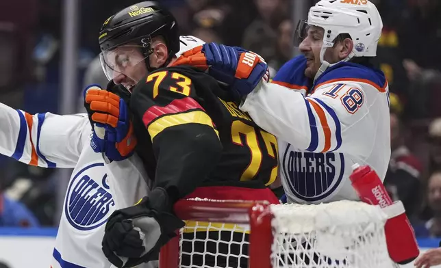 Vancouver Canucks' Vincent Desharnais (73) gets into a scuffle with Edmonton Oilers' Zach Hyman (18) and Connor McDavid, back left, during the first period of an NHL hockey game in Vancouver, on Saturday, November 9, 2024. (Darryl Dyck/The Canadian Press via AP)