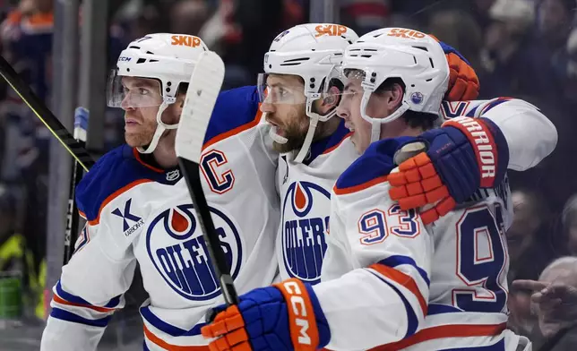 Edmonton Oilers' Connor McDavid, from left to right, Leon Draisaitl and Ryan Nugent-Hopkins celebrate Draisaitl's goal against the Vancouver Canucks during the first period of an NHL hockey game in Vancouver, on Saturday, Nov. 9, 2024. (Darryl Dyck/The Canadian Press via AP)